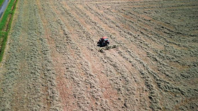 一架拖拉机翻动干草准备收割的航拍照片