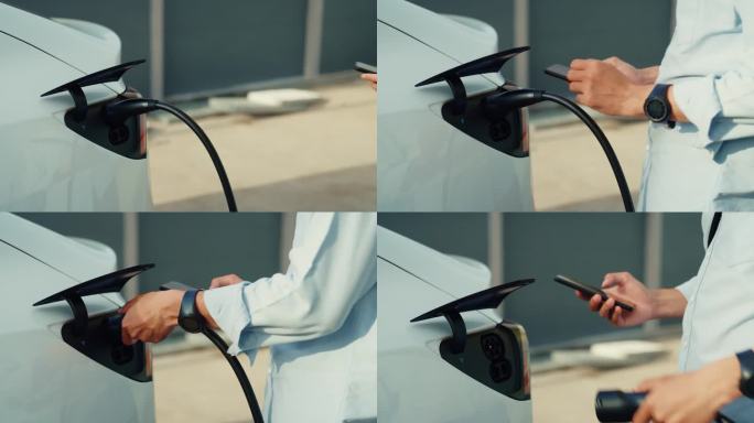 一名亚洲男子司机将电动汽车连接到电力系统，为汽车电池充电，并通过智能手机控制充电过程