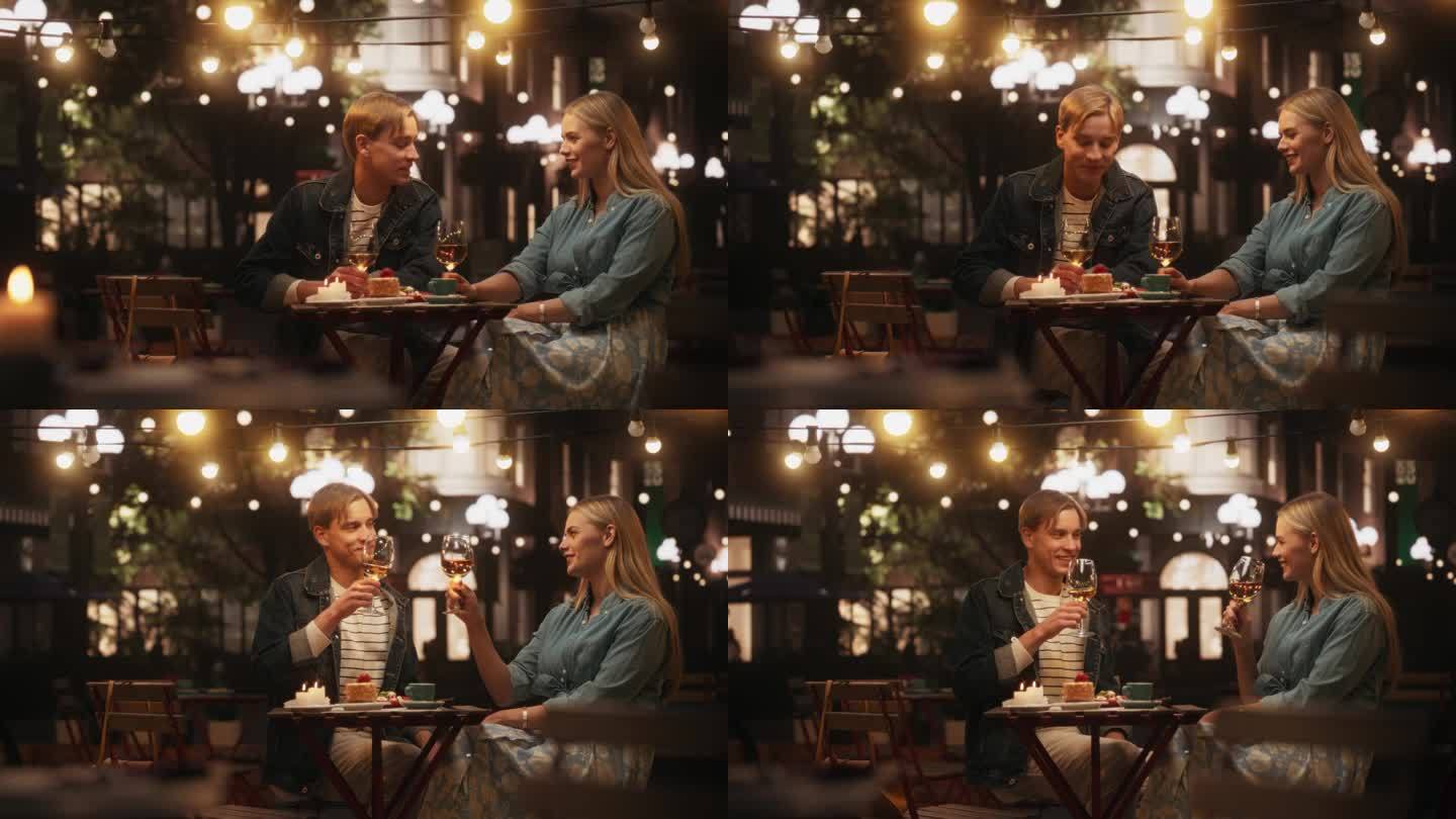 年轻漂亮的一对晚上在咖啡馆浪漫约会。快乐的男人和女人坐在露台上，举起酒杯，举杯并愉快地交谈