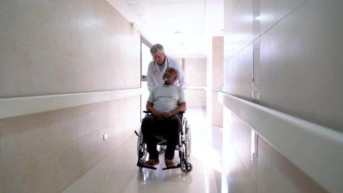一位心情愉快的医生带着轮椅上的黑人老年病人去医院做手术，与他交谈