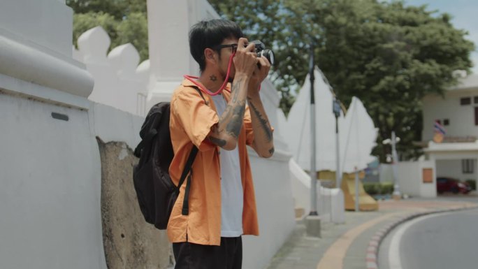年轻人背包客旅行观光曼谷地标。男子用数码相机拍摄图像。