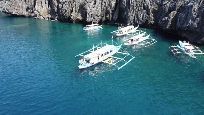 传统的支腿跳岛游船停泊在菲律宾爱妮岛的秘密海滩上。空中摄影车