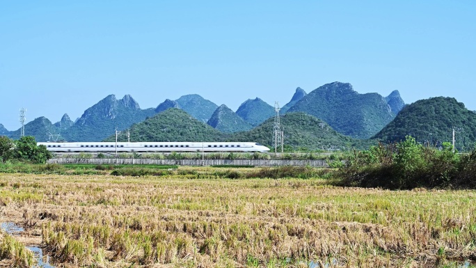 万里无云天空下桂林山边铁路上的高铁动车