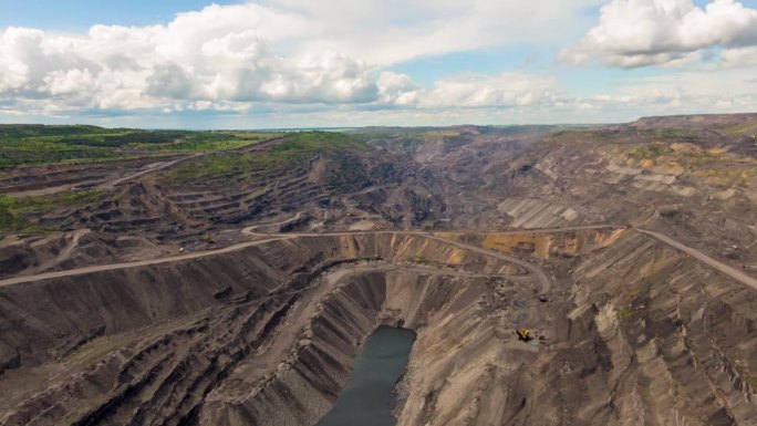 鸟瞰图时移露天煤矿采煤。露天采矿有大量的工作卡车和挖掘机。