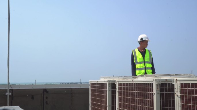 工技人员对工业楼顶室外风机空调进行检查