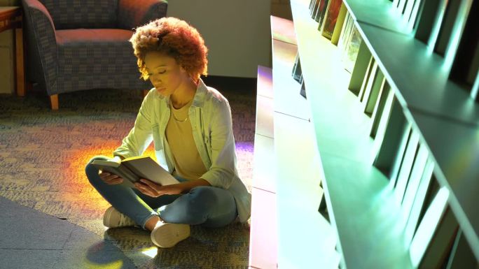 年轻的非裔美国妇女在图书馆看书