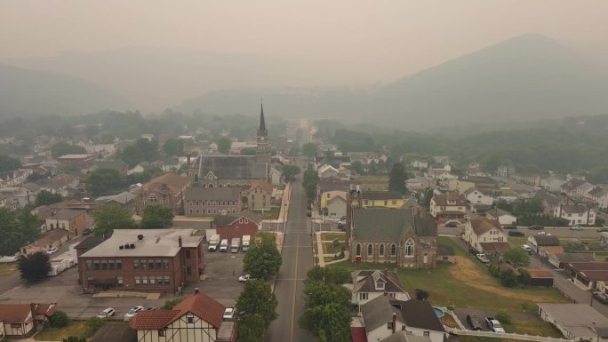 历史中心笼罩着烟雾，衬托着山景。宾夕法尼亚州波科诺斯阿巴拉契亚山脉吉姆索普上空烟雾弥漫的天空。航拍镜