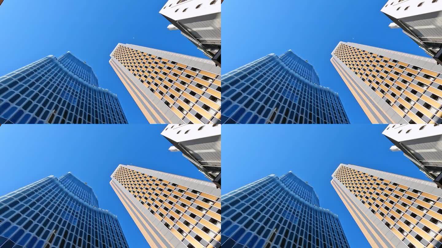 在新宿的东京金融中心，仰望令人印象深刻的未来主义摩天大楼。蓝色的天空