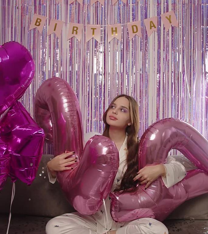 女孩坐在写着数字24的大气球旁，生日派对的垂直视频