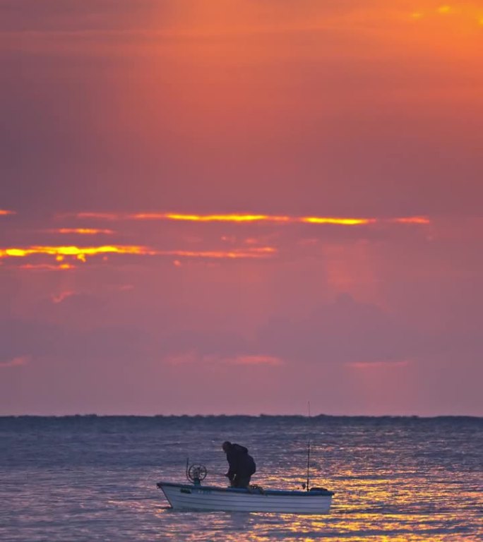 渔民在渔船上航行剪影设置网与日出水反射垂直自然视频