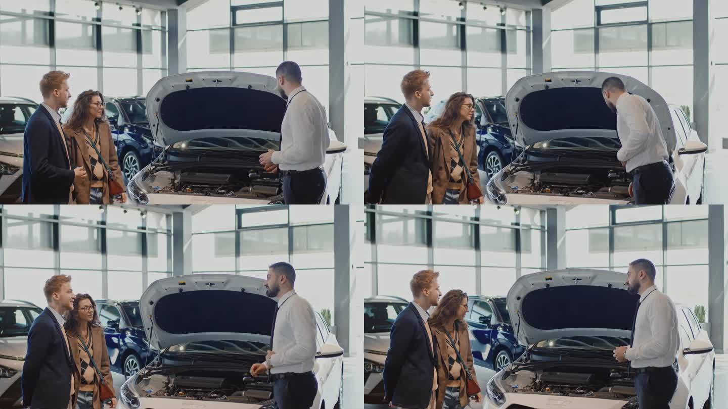 男销售经理在展示厅向夫妇示范汽车发动机