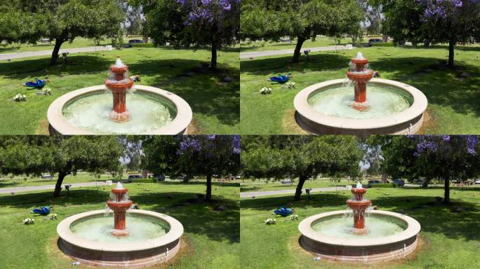 在加利福尼亚太平间，一个装饰喷泉被鲜花环绕，低空反向下降拍摄。4 k