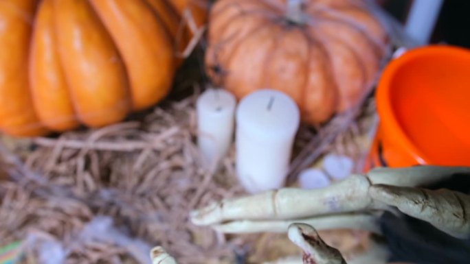 令人毛骨悚然的骷髅手万圣节幽灵要求将糖果倒入手掌，背景是南瓜和蜡烛