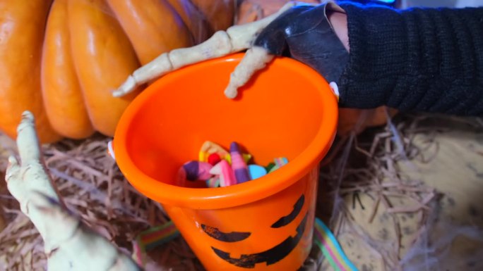 特写，穿着奇装异服的骷髅死亡人物在篮子里索要糖果和糖果，样式是橙色的南瓜