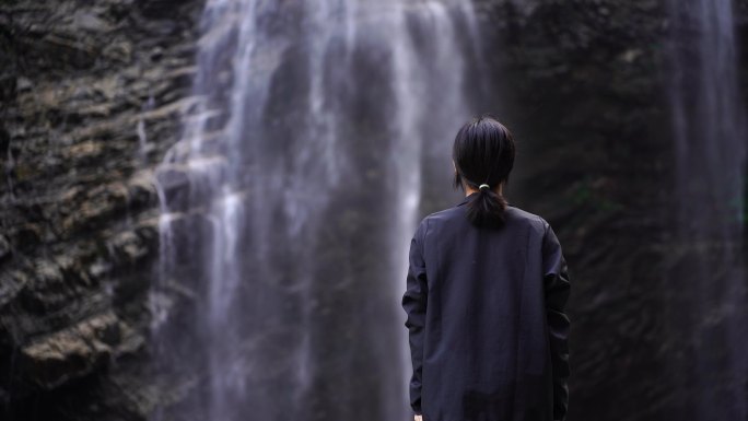 女性游客背影面向山水感受亲近自然山峰瀑布