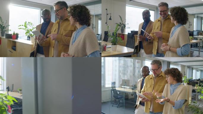 三个不同的同事走在办公室，看着平板电脑，谈笑风生