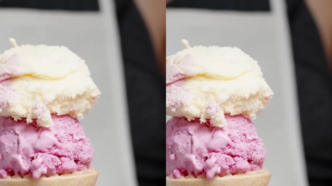 垂直视频。一个穿着白色围裙的女人用勺子把粉红色的冰淇淋球舀进华夫蛋筒里。