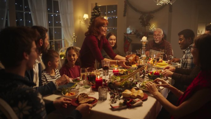 多元文化的亲密朋友和家人一起享受圣诞火鸡晚餐，一起度过节日。节日的晚上气氛，装饰圣诞树在家里
