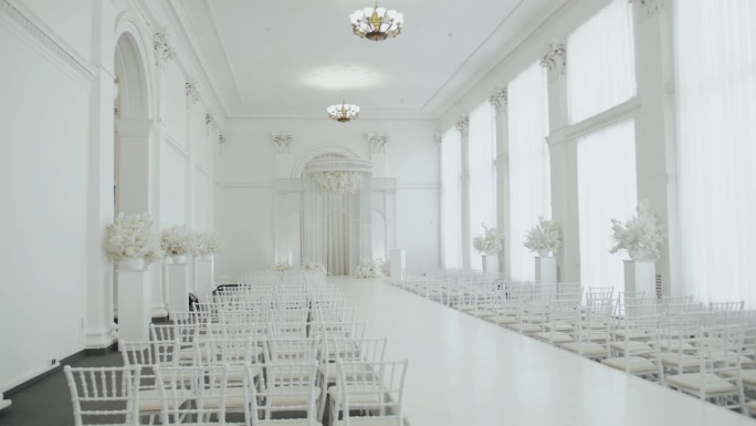 婚礼大厅装饰成白色，准备迎接宾客。美丽的房间为仪式和婚礼在白色的颜色，白色的椅子和白色的花卉组成。婚