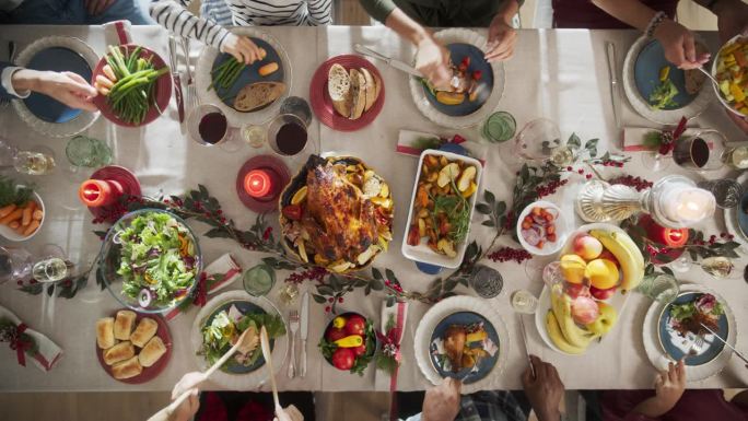 家庭成员，亲戚和亲人享受节日大餐，分享有趣的故事和喜悦在圣诞火鸡晚餐。从上到下的静态镜头，匿名的人在