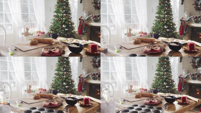 宁静的下雪的圣诞节早晨:在一个装饰着圣诞树、壁炉和礼物的现代房子的角落里，一张桌子上放着烘焙原料和器