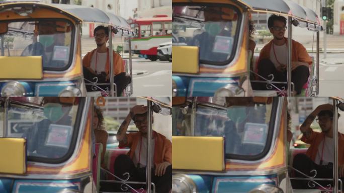 亚洲非洲妇女和亚洲男子游客坐在当地出租车叫嘟嘟车在旅游区观光曼谷著名的地方。