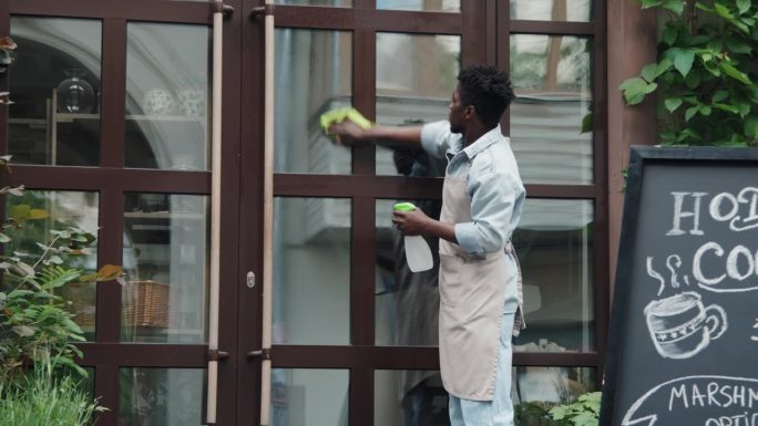 非裔美国咖啡馆工作人员在外面擦门