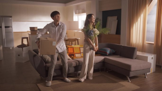 家庭搬家:幸福和兴奋的年轻韩国夫妇进入新购买的公寓。幸福拥抱的美丽家庭。准备好装饰的现代家居。按揭贷