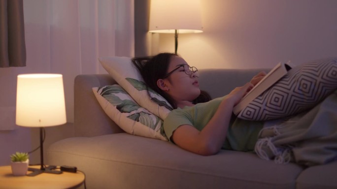 一位患有抑郁症和睡眠障碍的年轻亚洲女性在晚上睡觉前读书以改善她的生活。