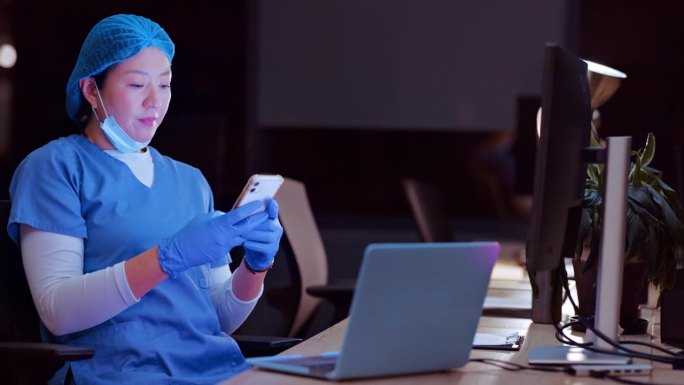 亚洲女性，医生和晚上用电话或笔记本电脑进行通信，网络或远程医疗在医院。女性，外科医生或医疗专业人员，