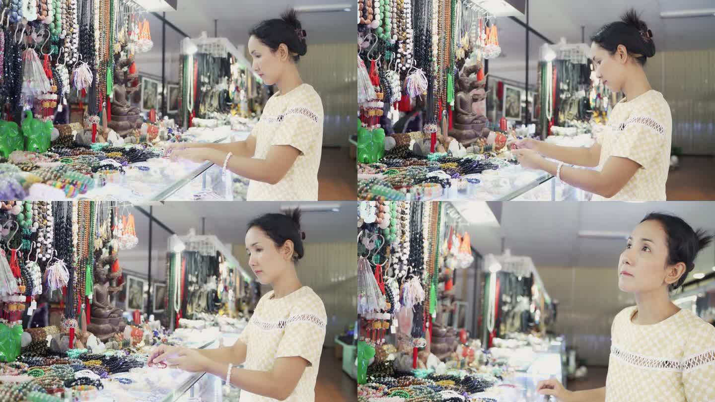 亚洲妇女在饰品店选购手工制作的手链或手镯。