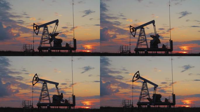 夕阳下无人居住的地区油泵工作的剪影。石油钻机和泵千斤顶。沙漠油田的石油钻井井架，用于化石燃料的开采和