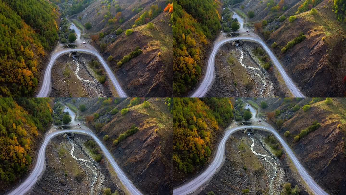 秋天，在五颜六色的树林里开车旅行。黑色轿车在峡谷中行驶的鸟瞰图。