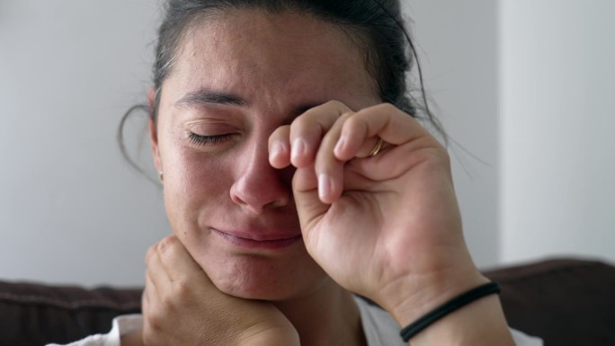 一个沮丧的女人在困难时期擦眼泪的画像。一个女人因失去亲人而哭泣的特写