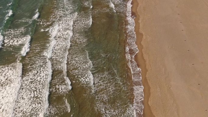 鸟瞰透明的蓝色大海，在夏天阳光明媚的日子里有美丽的海浪。热带景观从空气的海洋与蔚蓝的水，在日落沙底。