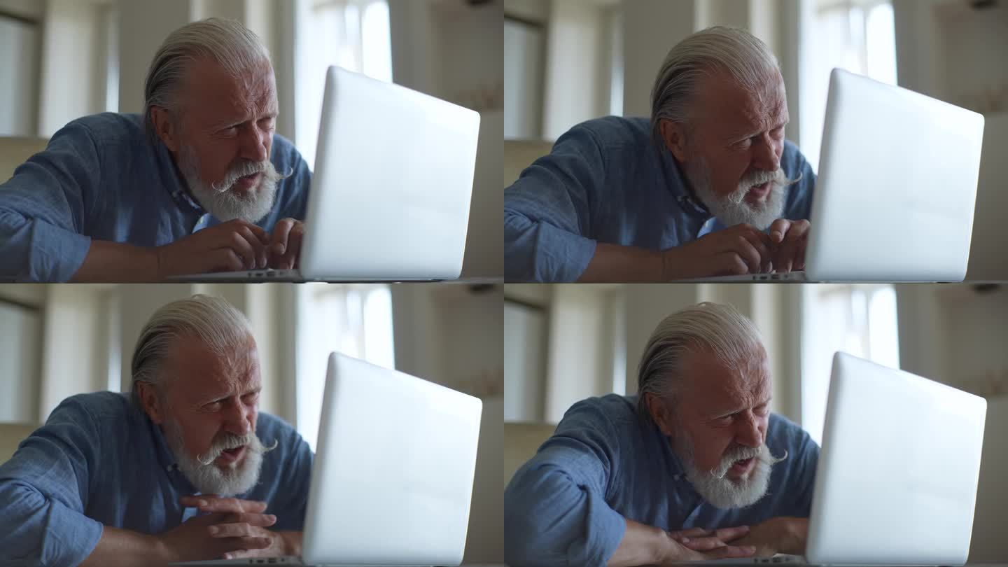 成熟的压力商人坐在笔记本电脑和关注的面部表情看着屏幕的特写。专注于高级计算机男性用户