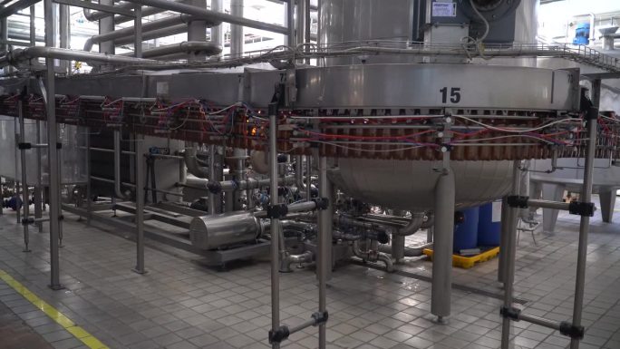 啤酒厂啤酒装瓶工艺流程。啤酒厂啤酒装瓶工艺生产线上，空铝啤酒罐正在传送带上移动