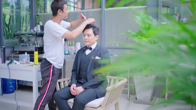 新郎在婚礼上由化妆师做头发和化妆。