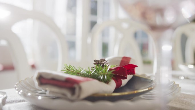 为庆祝感恩节或圣诞节的家庭晚餐准备的带有节日装饰的棉餐巾特写。桌子亚麻风格与松果和圣诞树枝