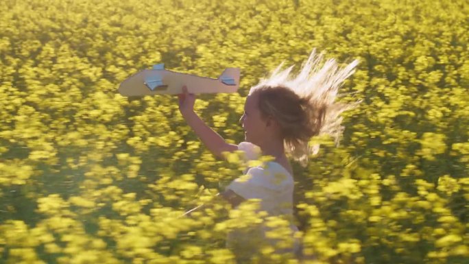 飞机，玩具和女孩在田野里奔跑，在乡下的油菜籽农场玩户外游戏。放飞飞机，梦想与孩子在鲜花中奔跑，暑假与
