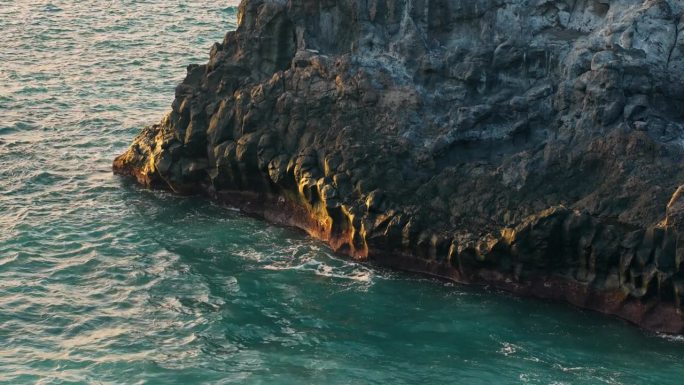 当海浪撞击岩石时，黄金时刻的光芒洒在被侵蚀的特内里费岛的海上悬崖上