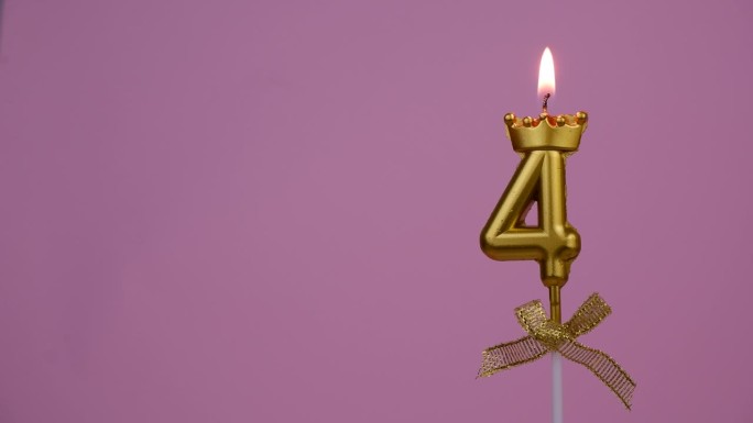 金色生日蜡烛在4号的粉色上燃烧。