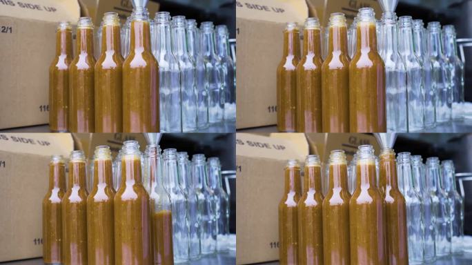 将辣椒酱装进玻璃瓶子，金属漏斗和盒子作为背景。美国工厂包装生产过程。