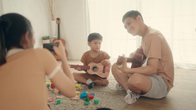 快乐的亚洲父子通过音乐联系在一起，在家里一起弹吉他