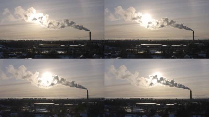 无人机镜头捕捉到区域供热厂冒出的滚滚浓烟和冬季日落的发光色调之间的相互作用，创造了一个视觉上令人回味