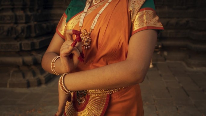近距离慢镜头拍摄印度女舞者的手做象征性的手势，在民俗舞蹈中传达不同的信息。穿着传统纱丽的女孩展示手印