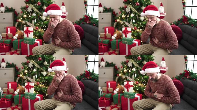 年轻的秃顶男子坐在家里的圣诞树旁忍受胃痛