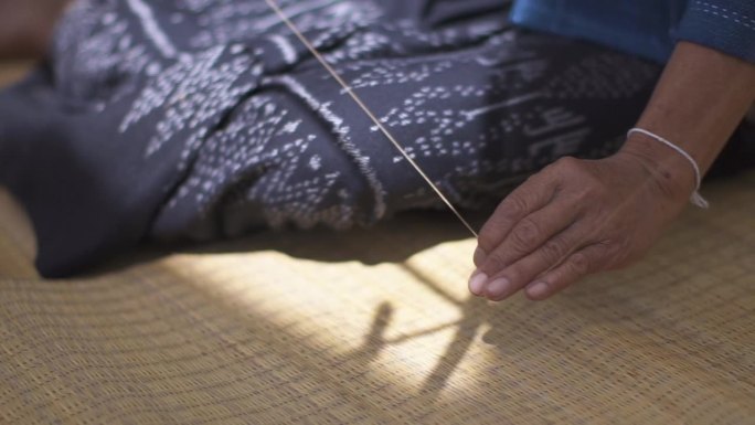 亚洲妇女手中握着一卷棉纱，泰国乡村文化生活。