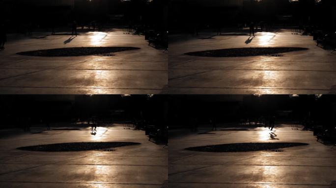 一个晚上在城市公园里骑滑板的人的剪影。