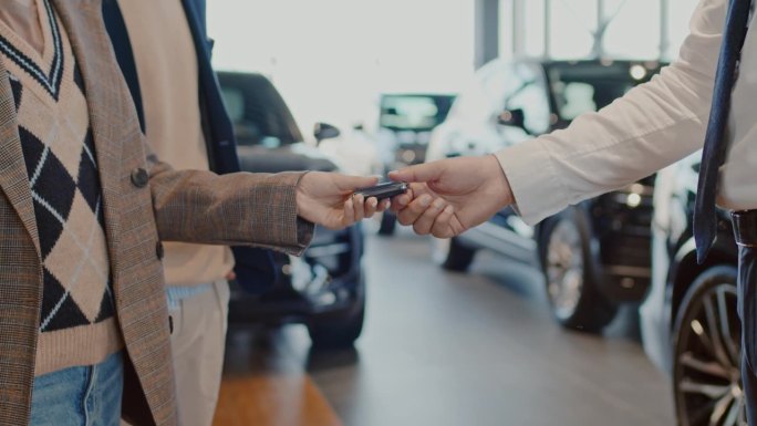 匿名汽车推销员给买家新车钥匙和握手